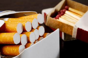 closeup of open pack of cigarettes and box of matches on background
