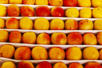 Juicy fruits of peach nectarines are spread out in even rows in the shop window