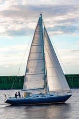 Blue sailboat against cargo ship