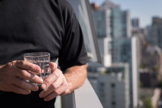 Man Holding Glass Of Water In The Balcony