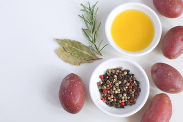 Olive oil porcelain plate Rosemary branch Pepper mix Bay leaf Raw potato Cooking concept White background Top view Copy space Flat lay