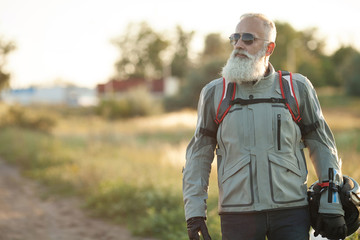 Handsome man in jean is holding a helmet and vintage motorcycle blur background