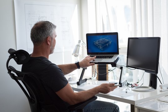 Man preparing architectural design on laptop and computer