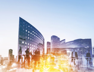 Silhouettes of people walking in the street near skyscrapers and modern office buildings in Paris business district. Multiple exposure blurred image. Economy, finances, business concept illustration