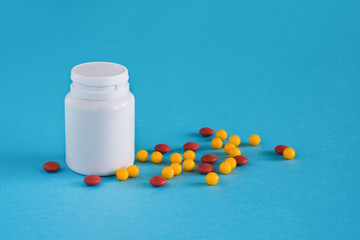 Medicine. Color capsules near pill bottle on blue background, top view copy space
