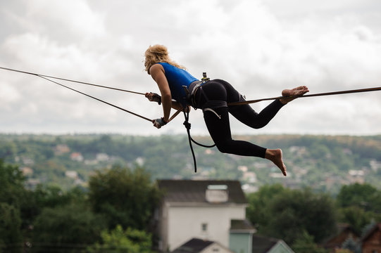 Young woman lying on the slackline rope on the bending knees