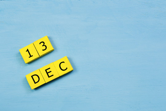 DEC 13, yellow cube calendar on blue wooden surface with copy space