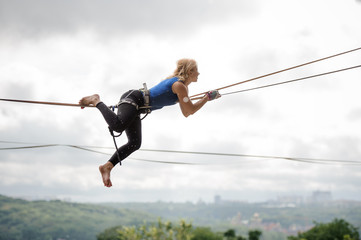 Side view woman lying on the slackline rope and looking into the distance