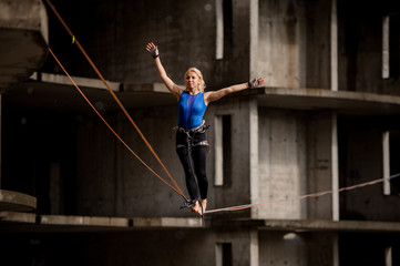Obraz na płótnie Canvas Female equilibrist balancing with arms raised on the slackline rope
