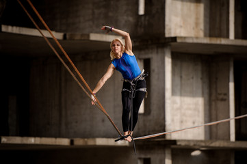 Female equilibrist standing tilted her hands in the right direction on the slackline