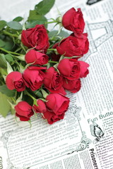 red roses bouquet is laying on old paper style background 