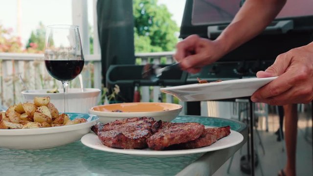 Man Self Serving Steak and Potatoes on a Summer Day in Backyard