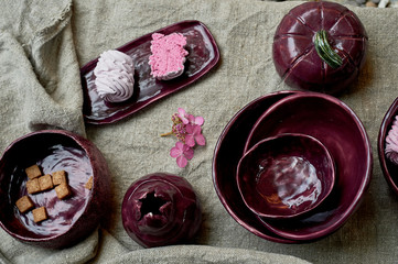 Set of handmade ceramics in purple on a piece of gray burlap. Rustic style. Clay modeling