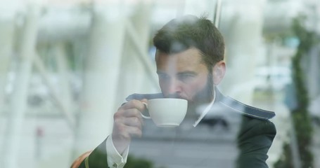 Attractive bearded pilot in uniform sits in café, smiles and uses smartphone. Being online, surfing the internet, social networks. Close up view, male portrait - Powered by Adobe