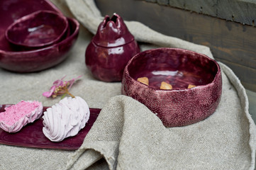 Set of handmade ceramics in purple on a piece of gray burlap. Rustic style. Clay modeling