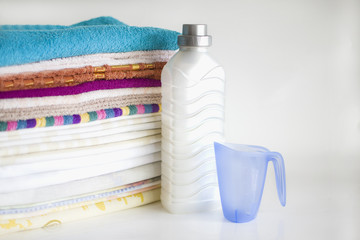 in the background the bottle of conditioner, a measuring Cup, a pile of towels