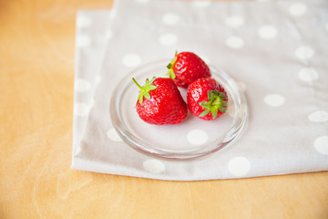 strawberries in a glass bowl on a wooden background and a beige napkin peas.