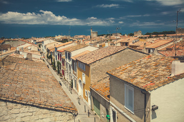 Fototapeta na wymiar Aerial view to tiled roofs and colorful facades of traditional fortified French village Aigues-Mortes