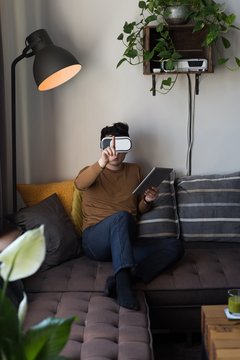 Man in virtual reality headset using digital tablet in living