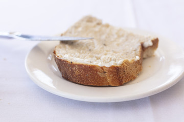 Slice of bread with a butter spread on a white plate