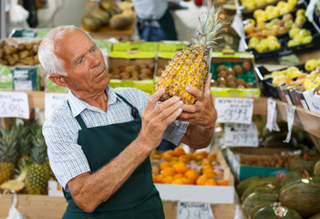 Seller putting products on shelves in greengrocery