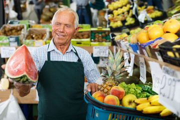 Elderly salesman working in greengrocery