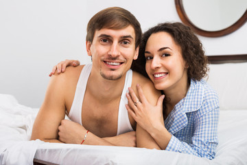 Fototapeta na wymiar Handsome young husband and wife posing in bed