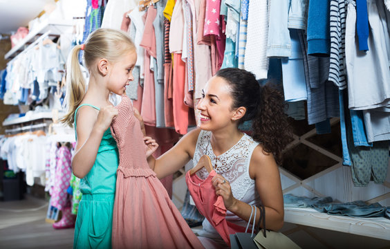 Young interested woman with small girl in kids apparel boutique