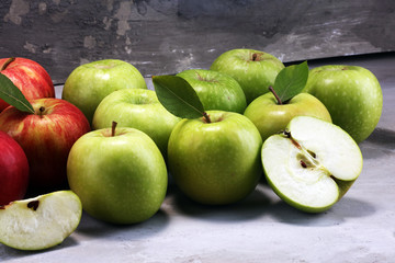 Ripe red apples with leaves on wooden background.