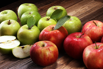 Ripe red apples with leaves on wooden background.