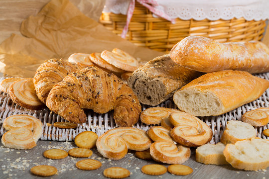 Wheat and grain baguettes, croissants and biscuits on wicker mat