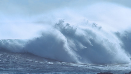 CLOSE UP: Large breaking ocean wave crashes and splashes near exotic island.
