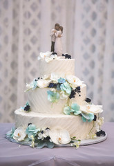 Fototapeta na wymiar Beautifully Decorated Wedding Cake with Bride and Groom on Top