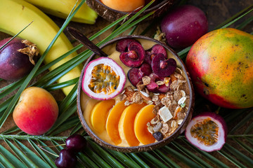 Smoothie bowl with fresh mango, passion fruit black cherry and granola