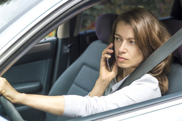 Young woman talking on the phone while sitting in the car. 
