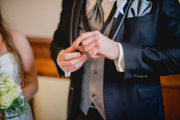 Groom putting wedding ring on bride's finger	