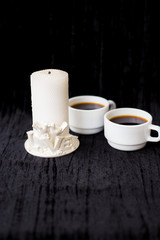 candle and two cups of coffee on a black background.