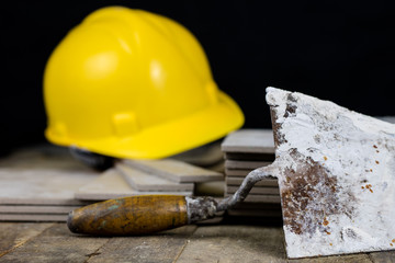Helmet, tiles and tools for the builder. Accessories for construction workers on a wooden workshop table.