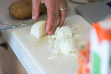 Woman dicing white or yellow onion on cutting board