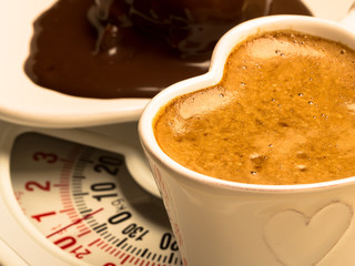 Coffee and chocolate cake on weighing scale.