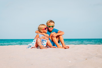 happy kids -boy and girl, brother and sister-hug on beach