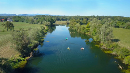Fototapeta na wymiar AERIAL: Flying behind a group of active tourists canoeing down a calm river.