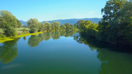 AERIAL: Flying along a beautiful river flowing through the vast countryside.