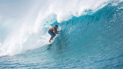 Cheerful young surfer enjoying the summer and surfing the big emerald waves.