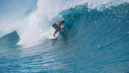 CLOSE UP Turquoise water splashes wildly behind fearless surfer riding in Tahiti
