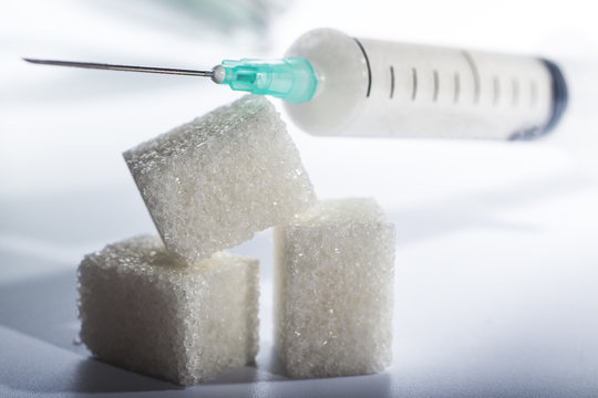 syringe filled with sugar lies on solid sugar cubes