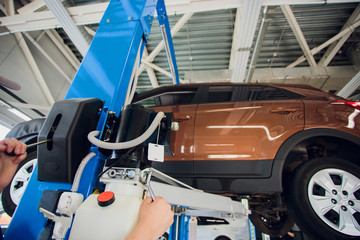 Mechanic in uniform lying down and working under car at auto service garage,copy space.