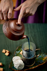 Tea with blue tea. Flower herbal tea. Women's hands, pours tea from the kettle in a glass with a Cup holder