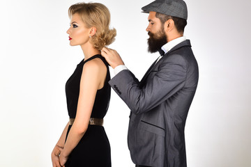 Romantic couple. Fashion couple. Love concept. Handsome fashionable man fastens dress charming girl in retro style. Woman in black dress&serious bearded man in grey suit. Retro couple in retro clothes