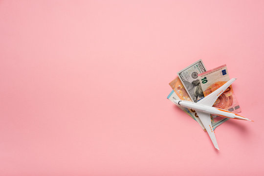 Plane And Money In Hand On A Pink Background.  Travel Concept.